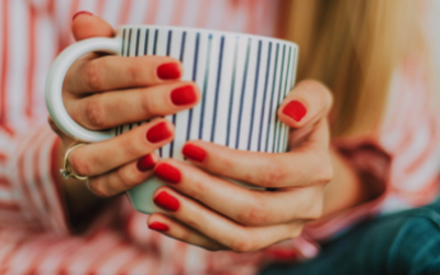 Woman in a red striped shirt holding a mug with red shellac gel polish