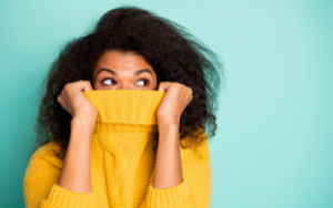 Woman in a comfy yellow jumper hides her face from the winter