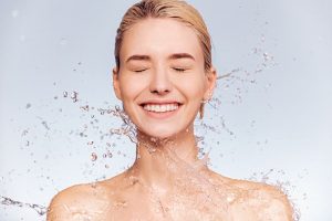 woman being splashed by water for skin hydration