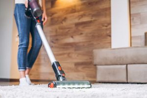 woman hoovering dust from the living room rug