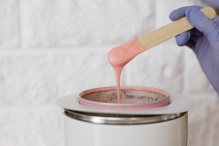 A bowl of pink hot wax being lifted up
